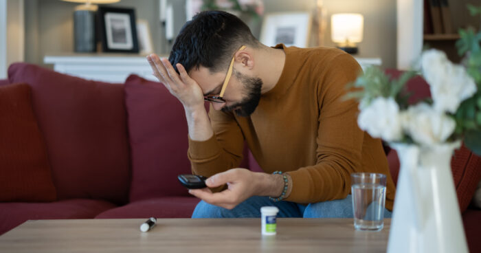 Stressed man checking blood sugar with glucose meter