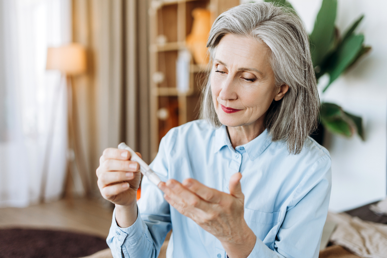 Senior woman using lancet pen for blood glucose test, performing diabetes control at home, managing blood sugar levels, preventing health complications, and promoting well-being in old age