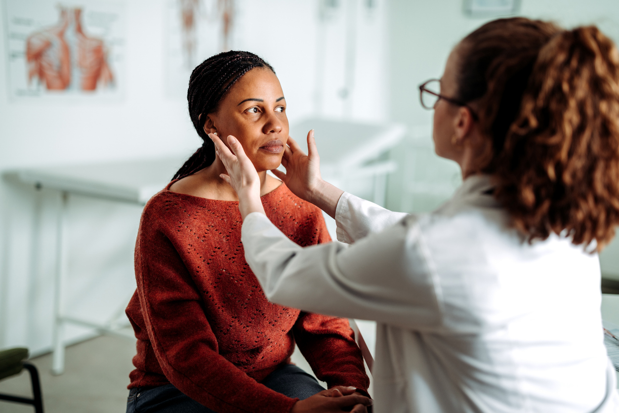 Female doctor examining lymph nodes on female patient at the office